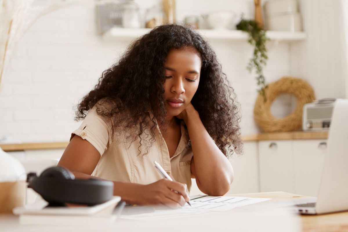 Une entrepreneuse remplit une facture à la main, à sa table de travail